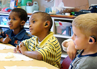 Three boys wearing hearing aids in a classroom