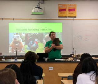 Adult holding an animal at the front of a classroom