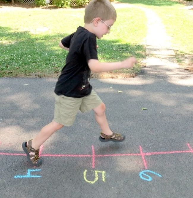 Young boy running on a chalk number line on a sidewalk