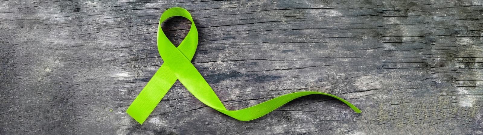 green ribbon on grey wooden background