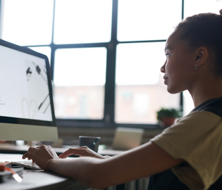 Young woman typing on an iMac computer