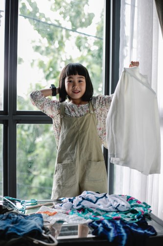 a young girl standing in front of a window looking through outfits