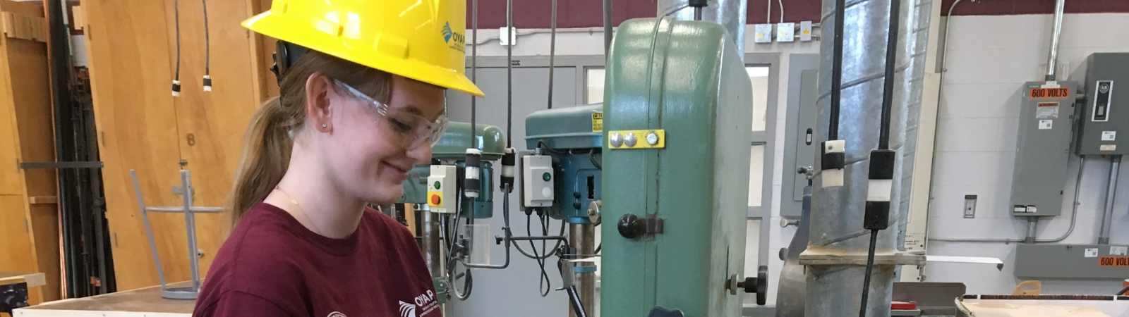 student in hard hat working with saw