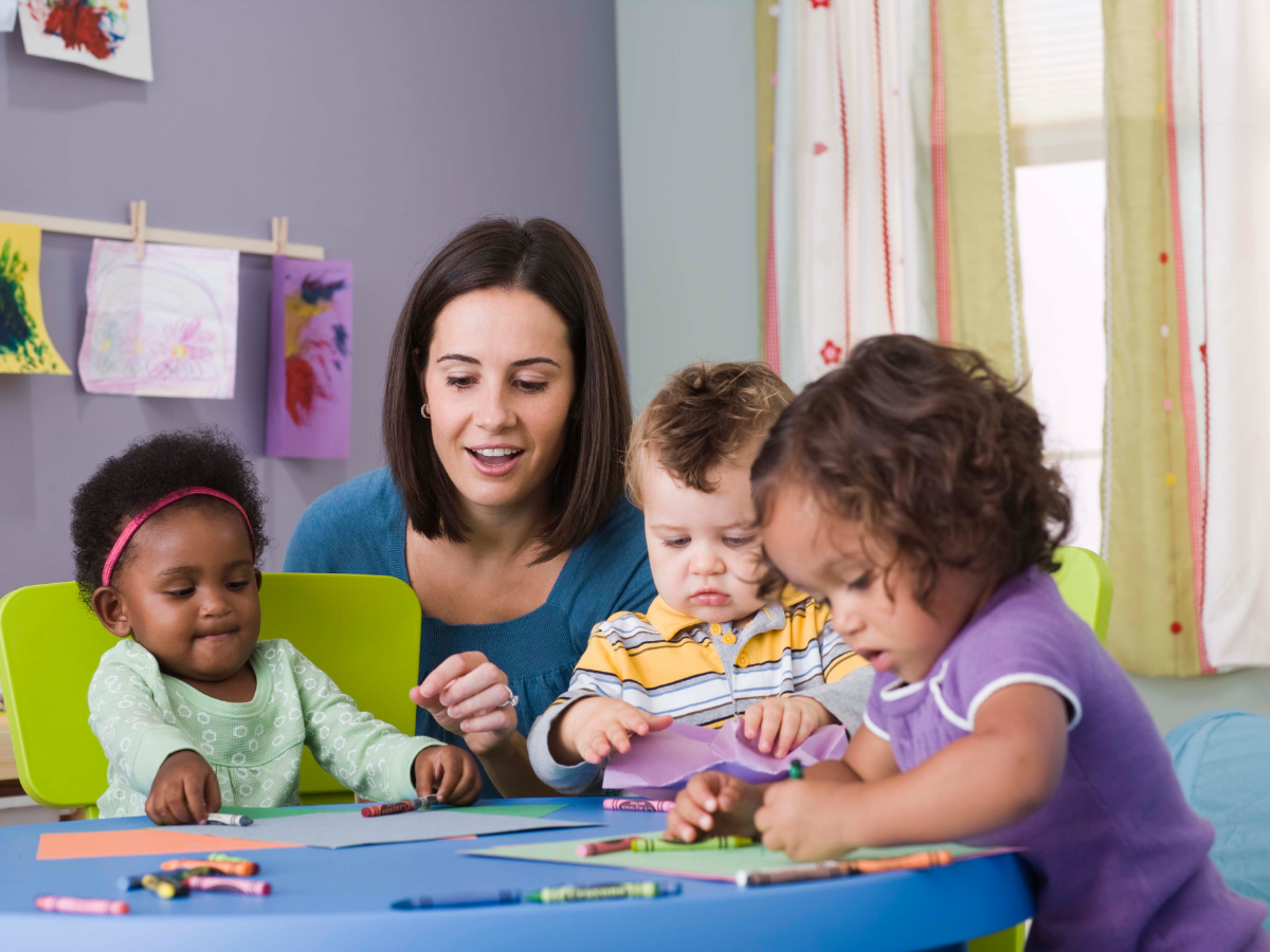 teacher sitting with students at desk