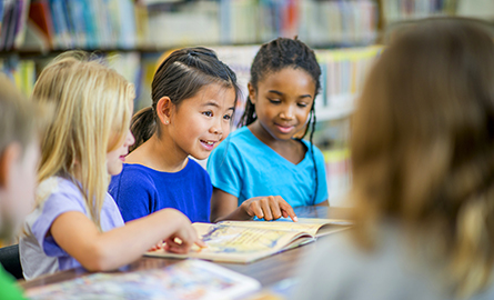 Three female students looking at a look in a library