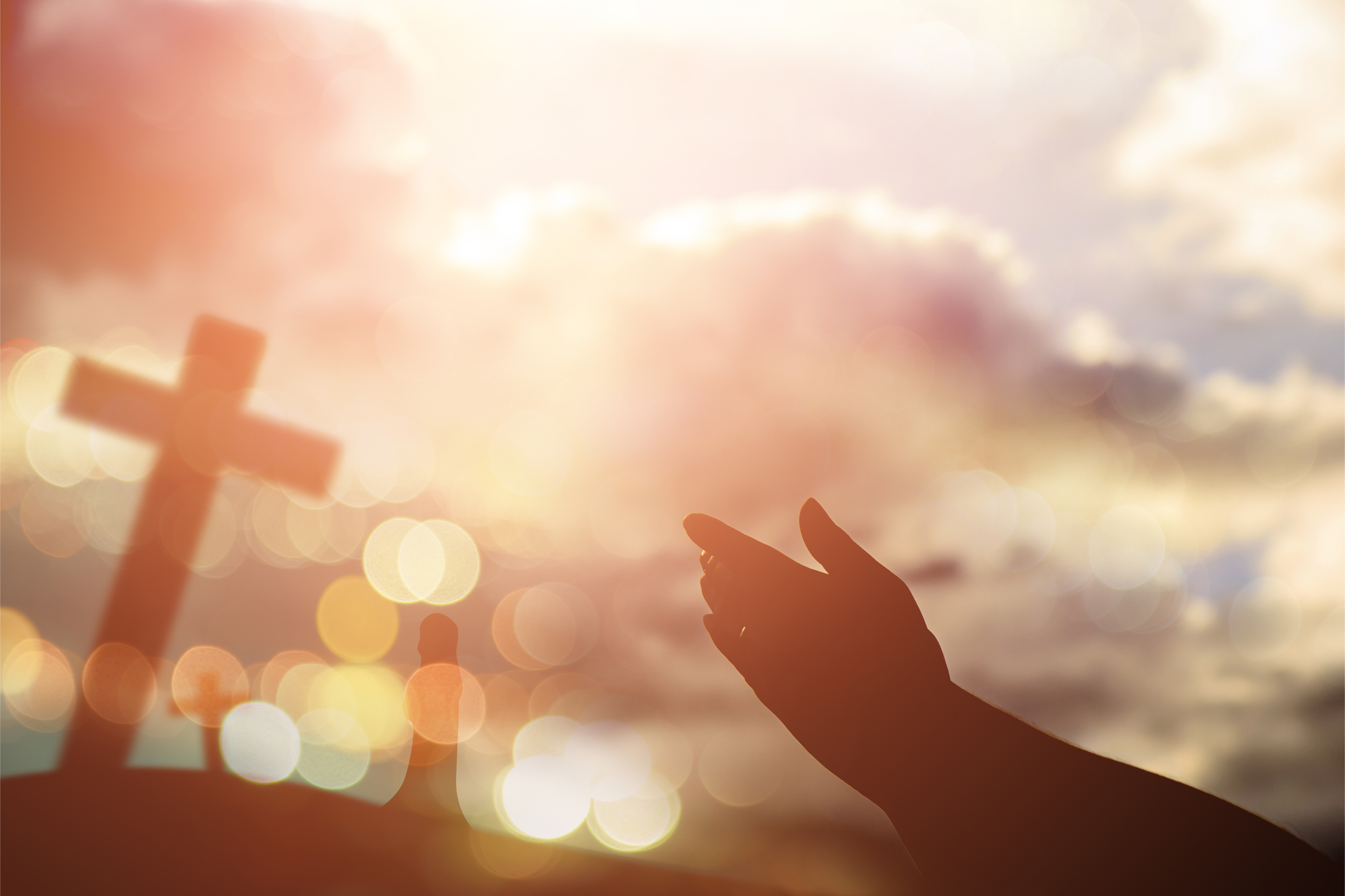 Hands pointed to wards a cross and the sky