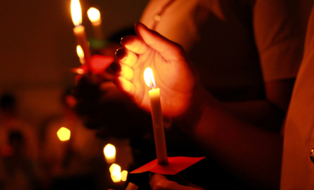People holding lit candles in the dark