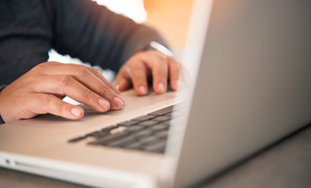 close up of a mans hands on a keyboard of a laptop