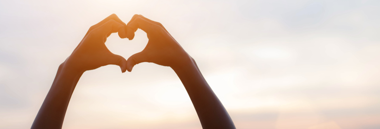 photo of hands in the air making the shape of a heart with fingers