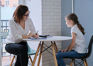 Female adult talking to a female student at a table