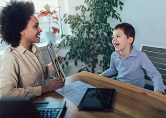 Female adult helping a male student make sounds