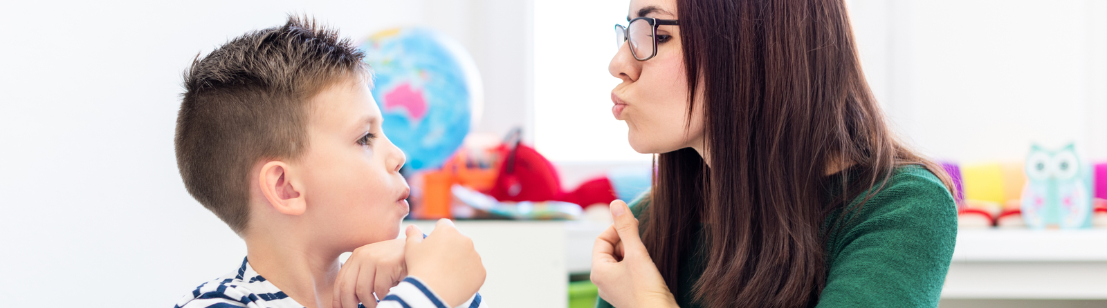 Female adult helping a male student to sound out words