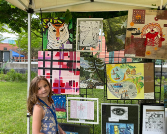 Female student standing beside her artwork at festival