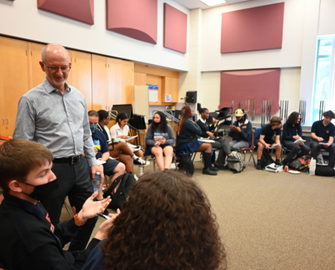 Male Trustee talking with secondary students about board's multi-year strategic plan