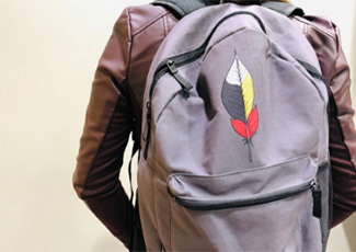 Feather on a backpack in the medicine wheel colours