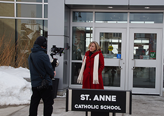 Female adult on camera in front of St. Anne Catholic School