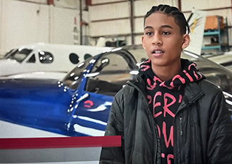 Male student standing in front of airplanes