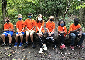 Students wearing orange shirts and masks learning on the land