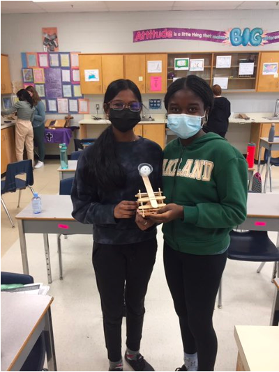 Two female student stand with the capulet they built
