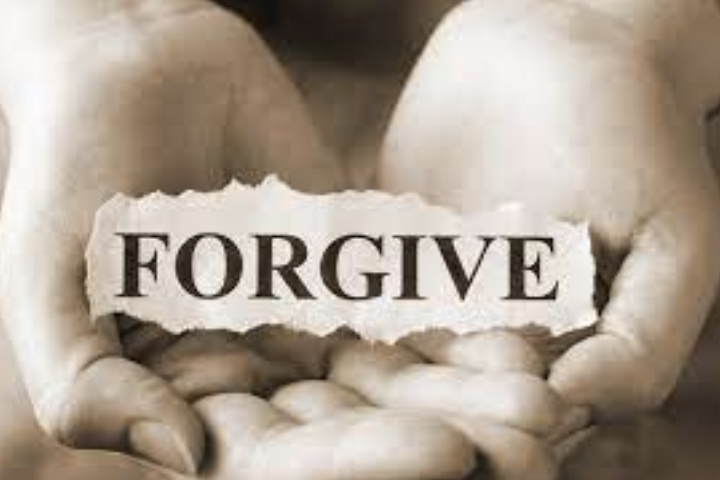 hands holding a piece of paper with the word forgive in the center