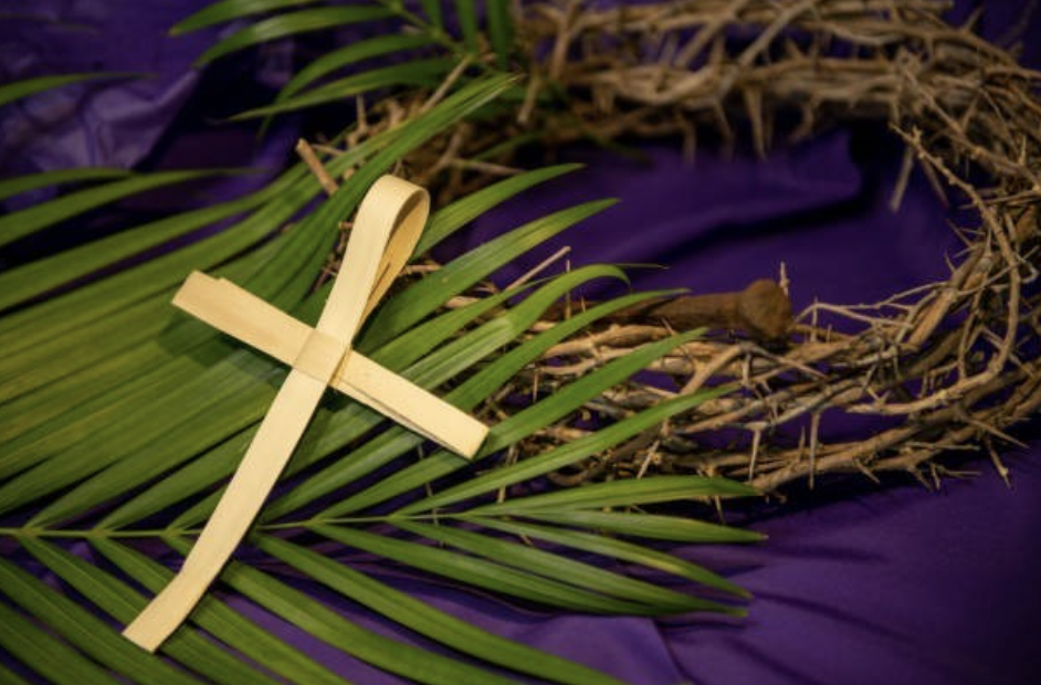 a cross laying across green palms