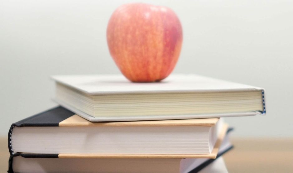 A red apple on top of a stack of books