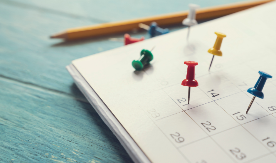 paper calendar with thumb tacks on a desk