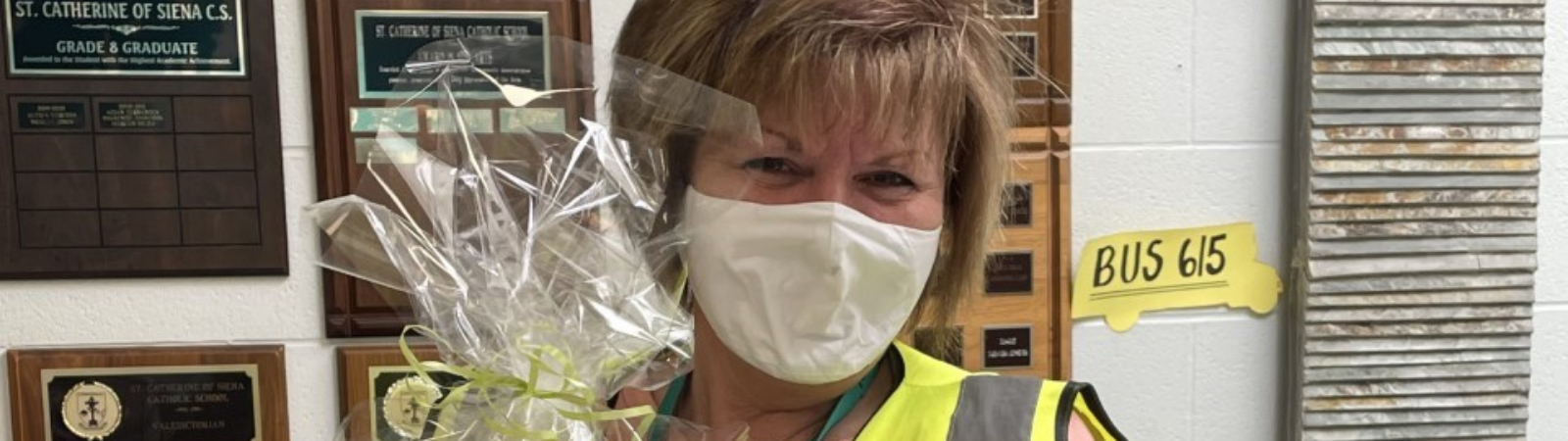 woman smiling and wearing a mask while holding bouquet of flowers