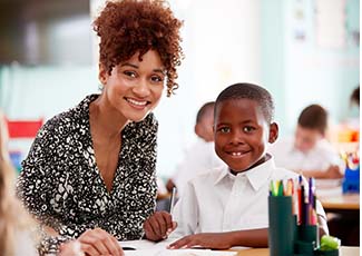 Female adult helping a male student in a classroom