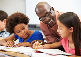 Male teacher talking with two female students in a classroom