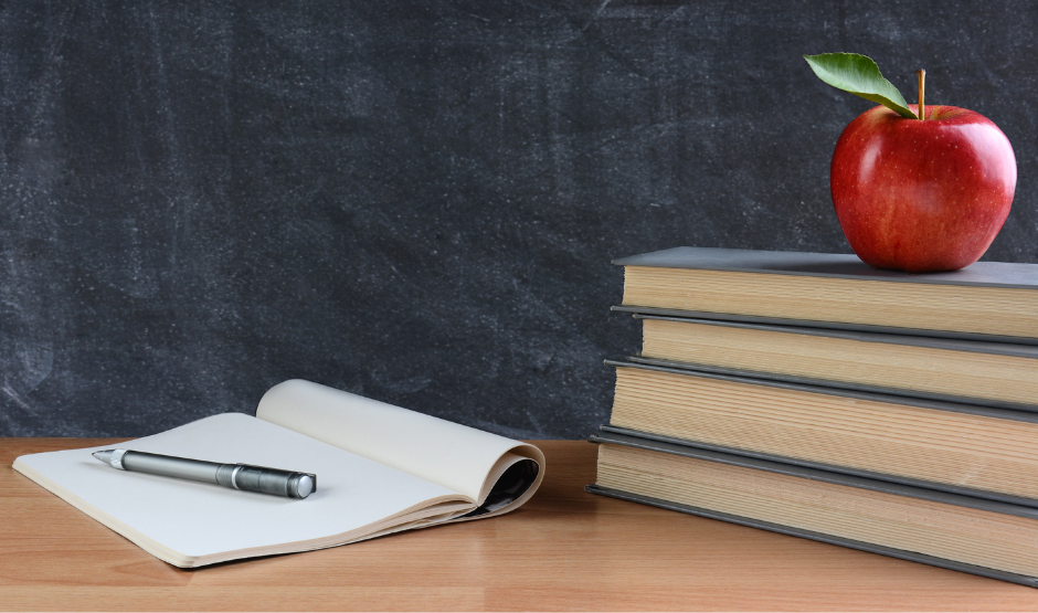 Open notebook and pen on a desk and a red apple