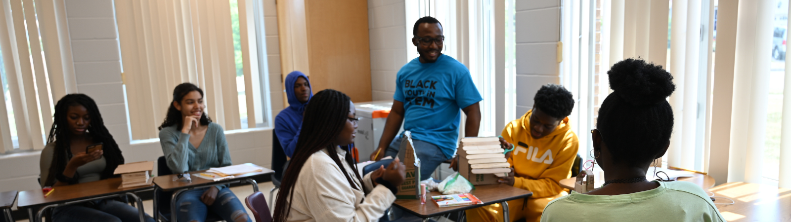 Adult male helping teen students build structures