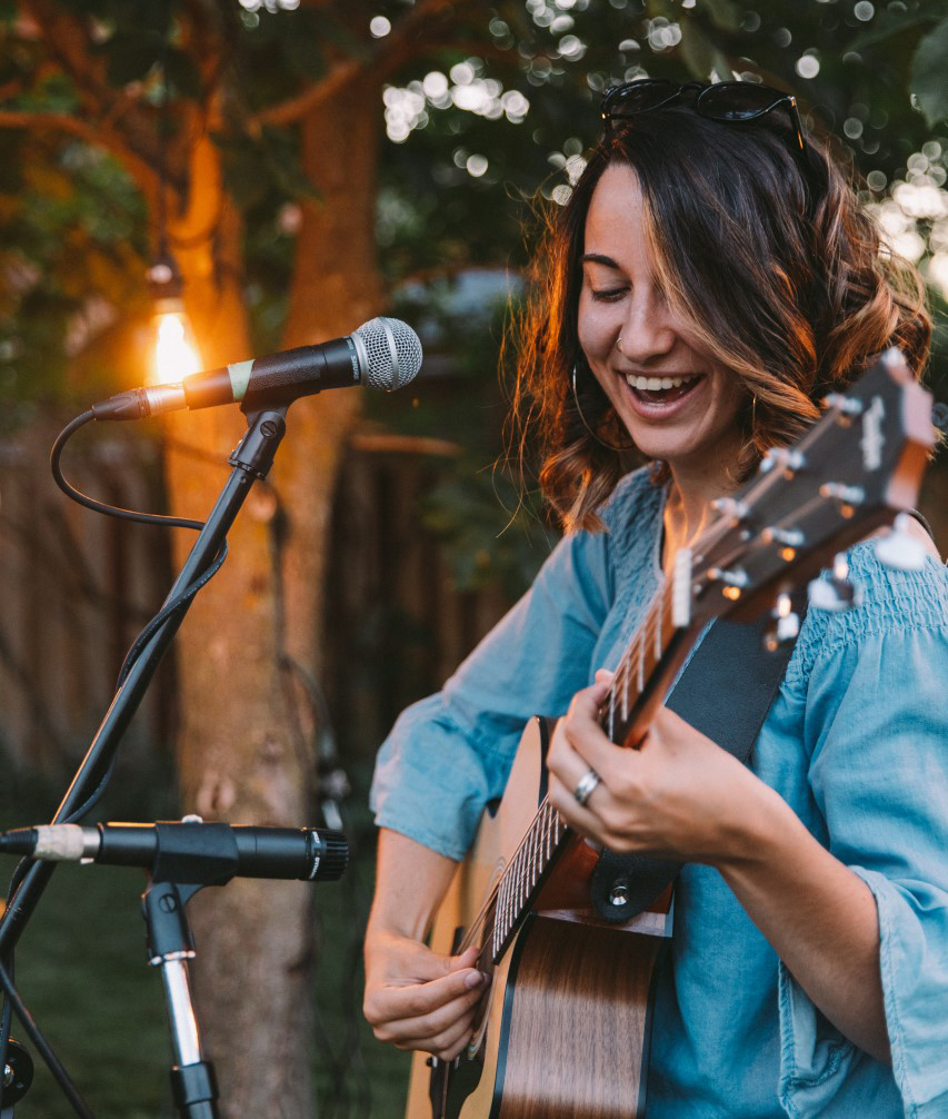 female adult smiling and playing guitar
