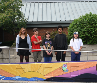 Students standing in front of a mural