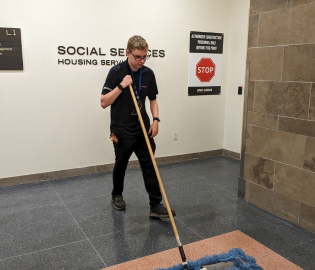 Male student sweeping the floor