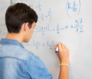 Teen boy solving a math problem at a board