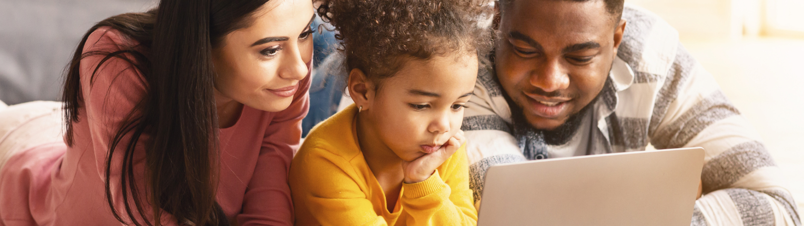 Two parents and their daughter looking at a laptop