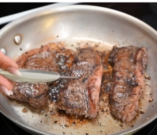 Close up of a steak cooking in a frying pan