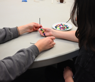 student placing a bracelet on another students wrist