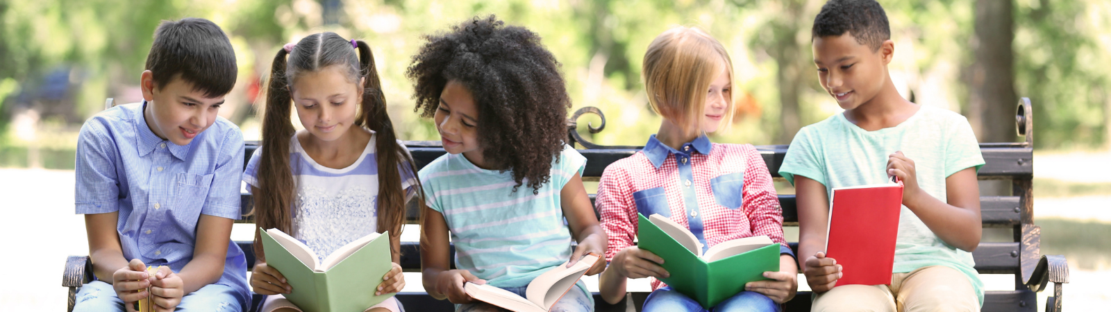 a group of kids sitting on a bench reading bokos