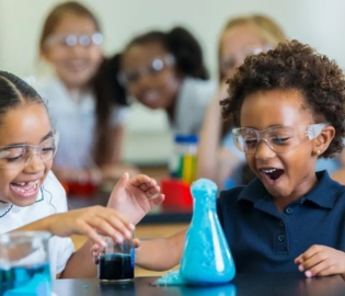 Two children smiling, using science supplies