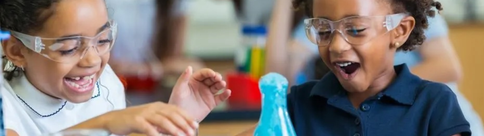 Two children smiling, using science supplies