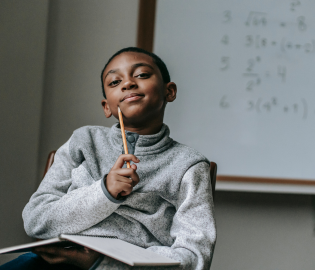 Student sitting holding a pencil and book