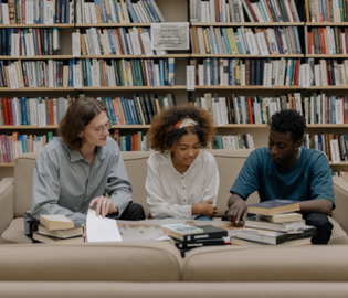 students sitting at table looking at book