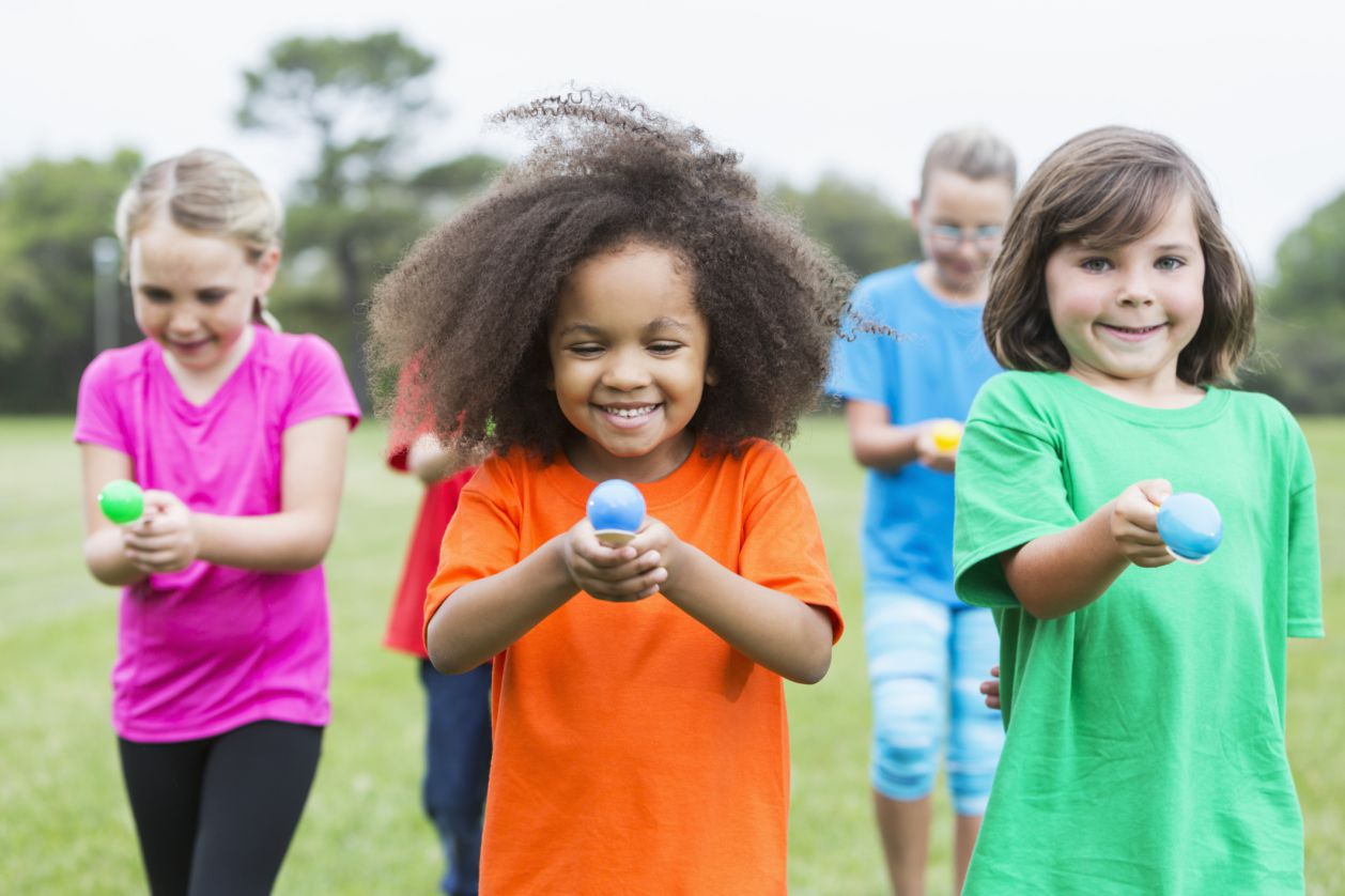 Girls and boys walking with spoons holding an egg outside