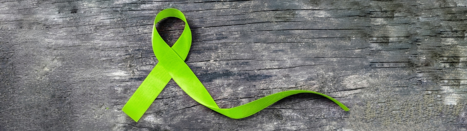 green ribbon on grey wooden background