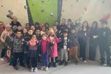 kids standing in front of a rock climbing wall