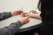 a student tying a bracelet on another students arm